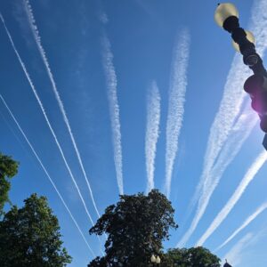 White aircraft trails radiating across a blue sky