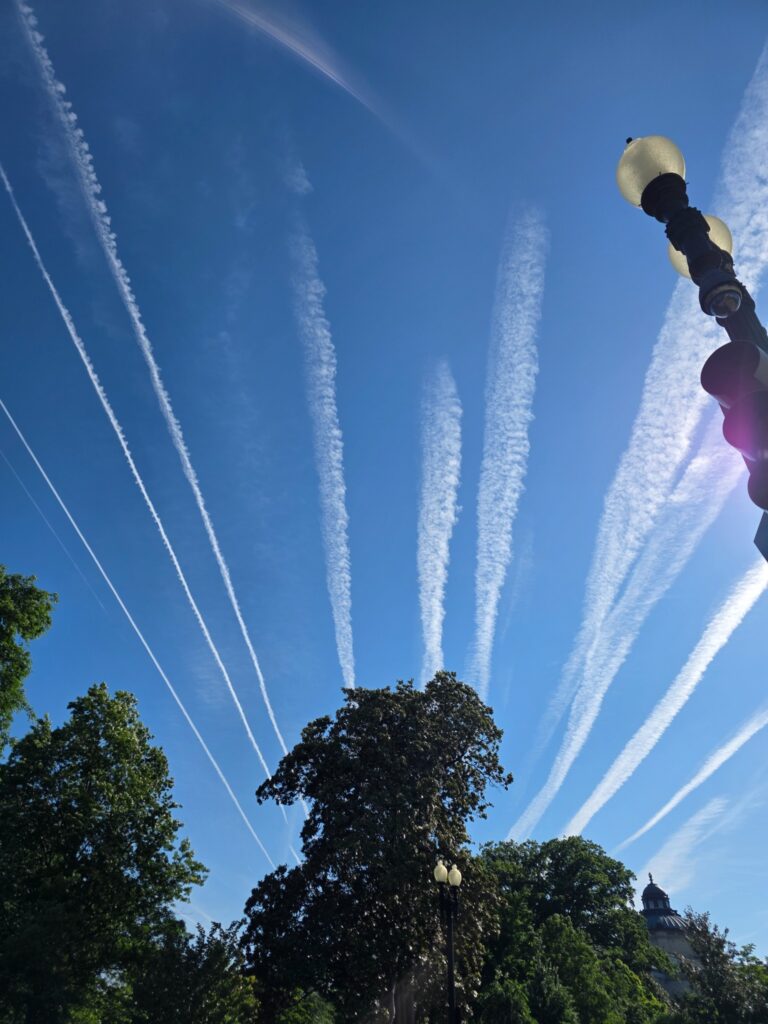 White aircraft trails radiating across a blue sky