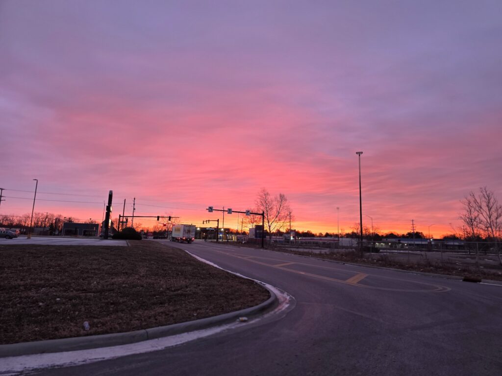 Pink and orange dawn above an open roadway