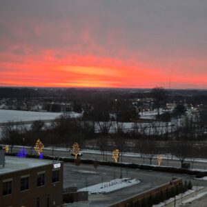 Orange winter sunset above rooftops and a snowy landscape