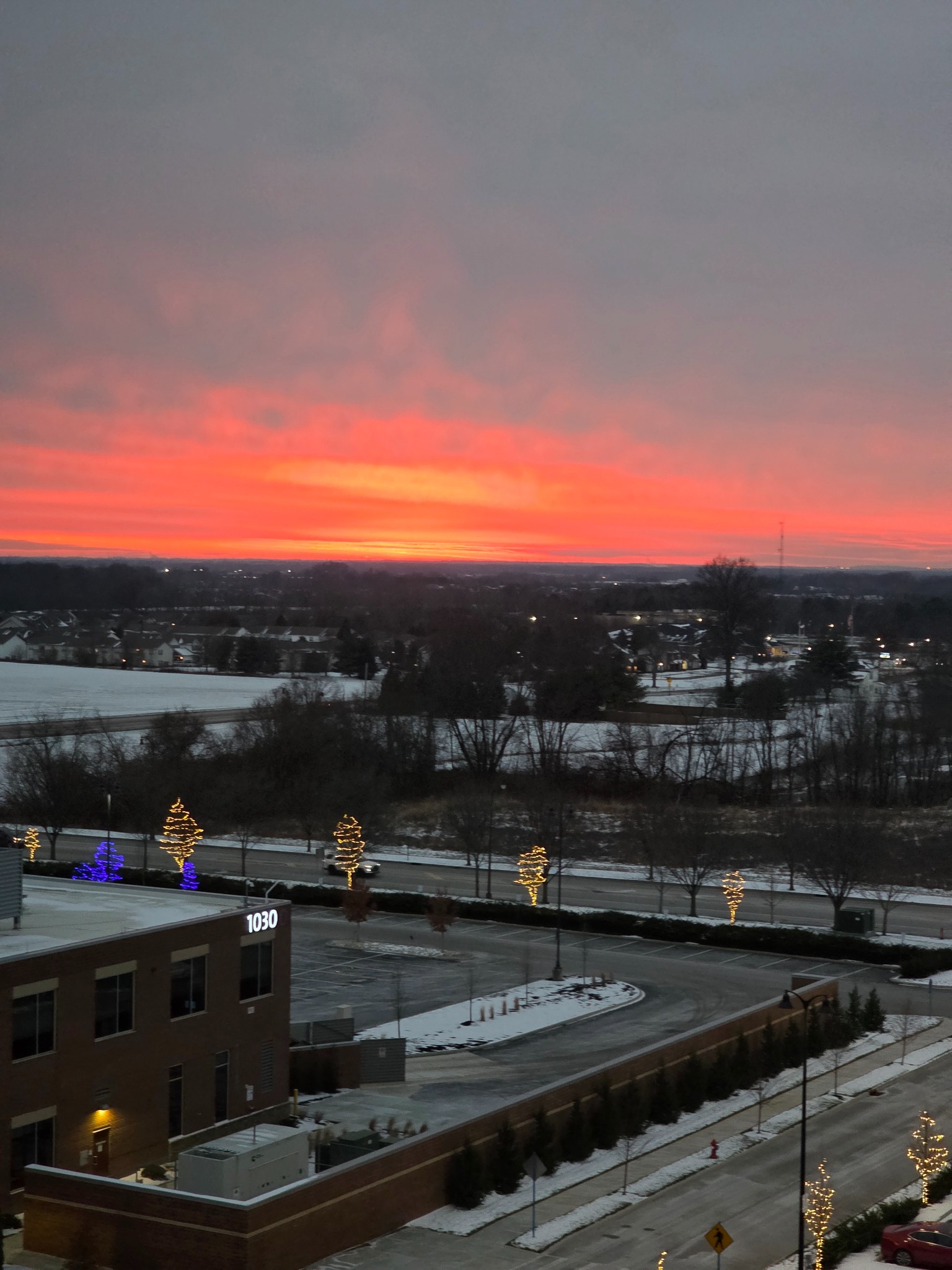 Orange winter sunset above rooftops and snow